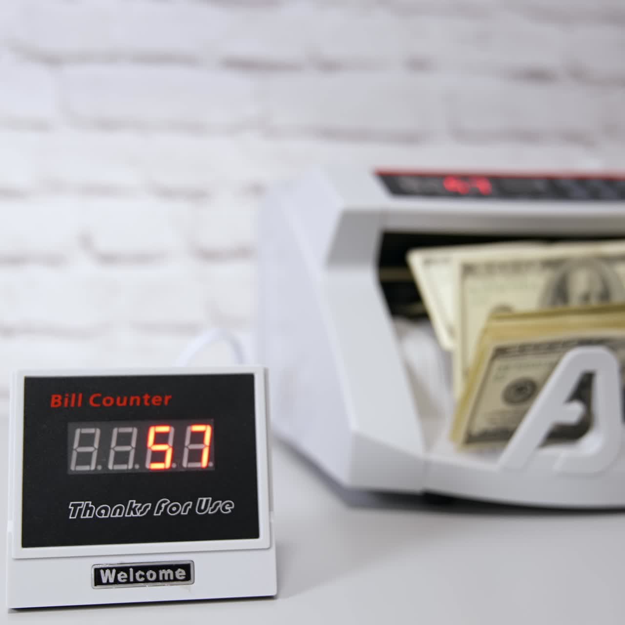 Bankadaki elektronik cihazlar. Sayım makinesinde banka işlemleri. Banka finansal işlemleri için otomatik mekanizma. Kadın eliyle bir deste doları para sayma makinesine koyuyor.