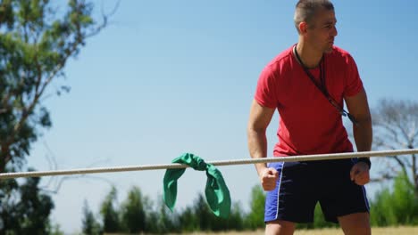entrenador ayudando a los niños en el tira y afloja durante el entrenamiento de cursos de obstáculos