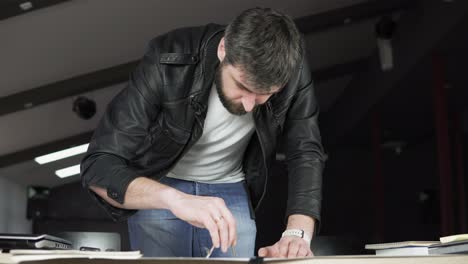 Young-man-working-on-a-project,-drawing-and-thinking-in-modern-office.-Using-compass.-Shot-in-4k.