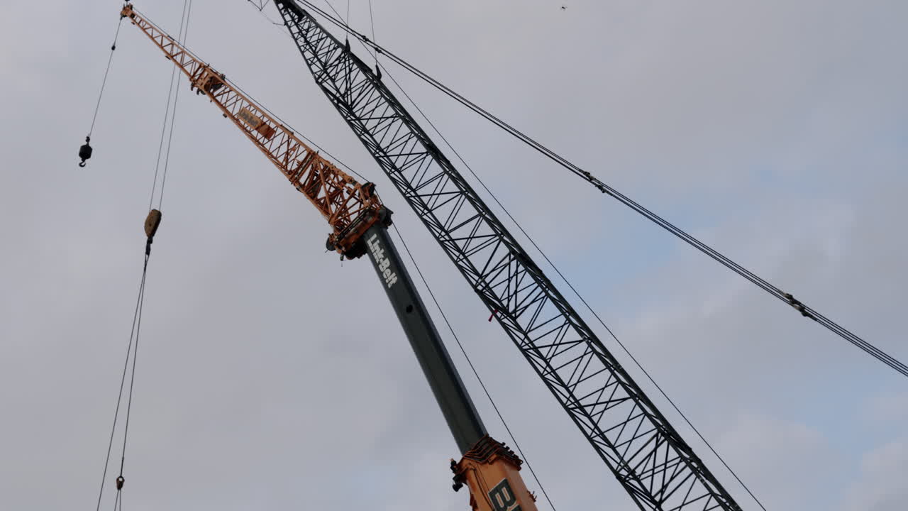 Two large cranes against a cloudy sky