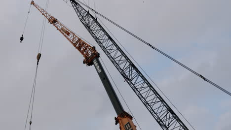 two large cranes against a cloudy sky