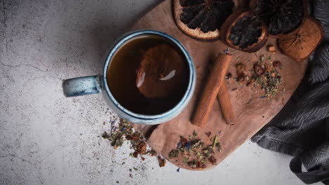 top view of hand putting cup of steaming tea on wooden plate