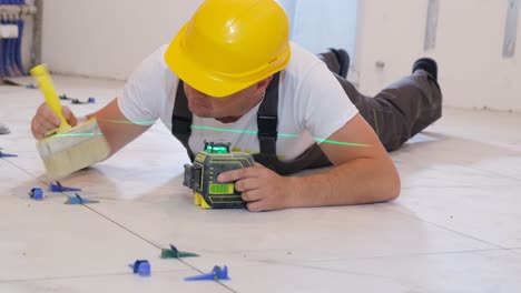 a craftsman in a yellow helmet lays ceramic tiles on the floor