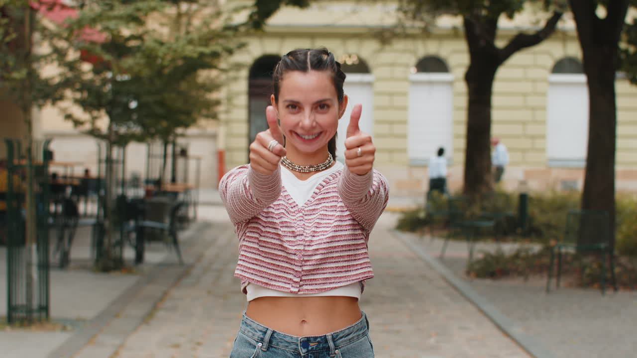 Woman showing thumbs up like sign positive something good positive feedback in urban city street