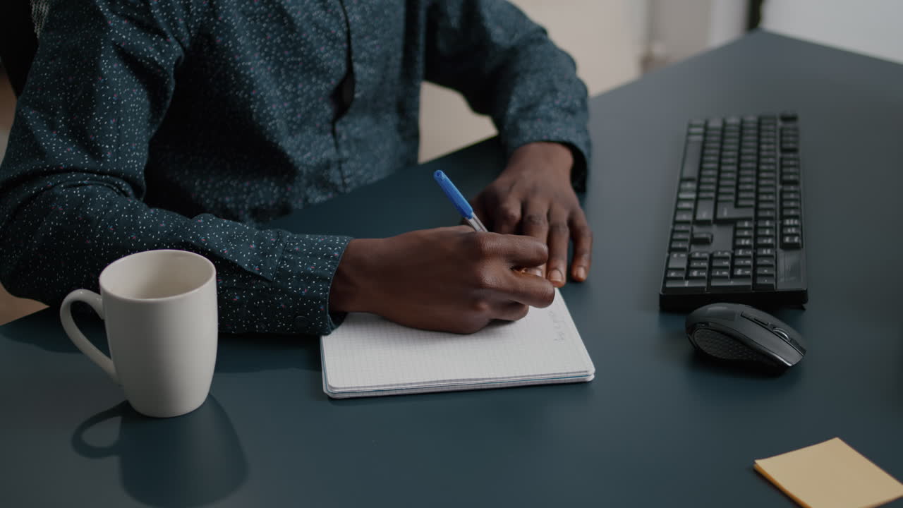 African american black person writing notes on notepad using a pen