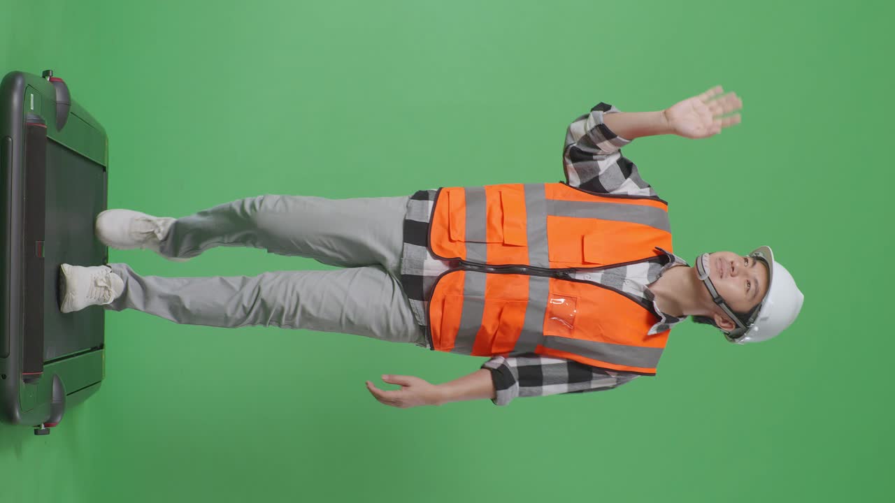 안전 헬을 입은 아시아 남성 엔지니어의 몸이 녹색 스크린 배경 스튜디오에서 는 동안 손을 흔들고 있습니다.