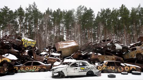 War-ravaged Irpin: Burnt car wreckage piled high, stark reminder of Ukraine-Russia conflict. Winter scene captures aftermath of fierce battles, showcasing urban destruction in ongoing war zone.