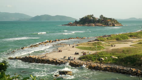 vietnamese people enjoy walking on large stacked stone clusters protecting beach from big ocean waves near hon chong, nha trang, vietnam