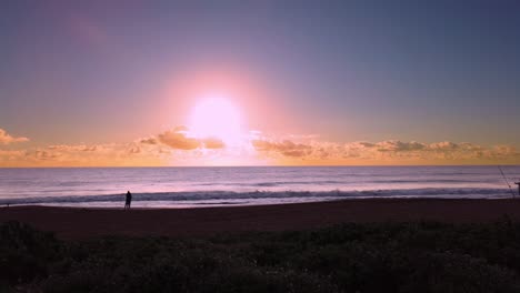 UHD Hawaii Kauai HYBRID timelapse static of couple in distance on beach watching sunrise. Sunrise is timelapse, couple watching and ocean waves in normal speed.  Perfect to add zoom for HD project!