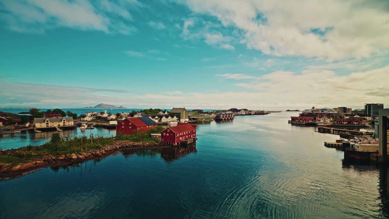 Picturesque nordic landscape. Lofoten islands, Norway.
Blue cloudy sky reflecting on the still sea. View of the red fishermen cabins.