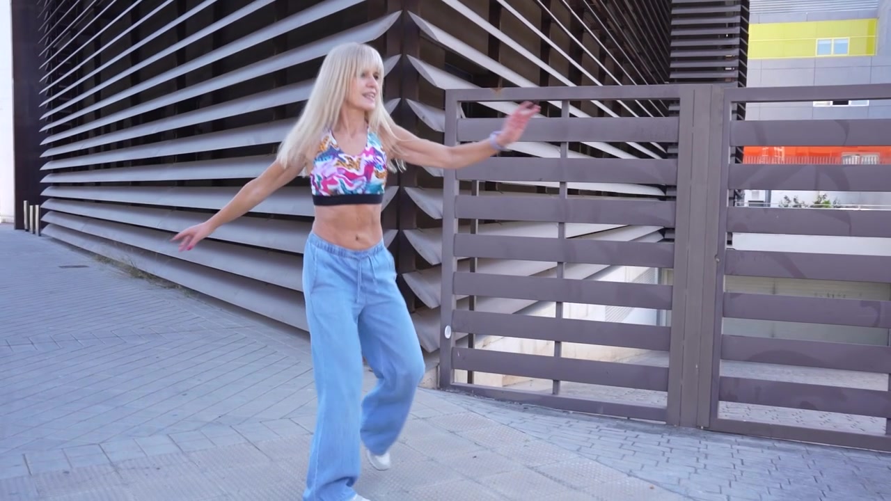 Una giovane donna balla all'aperto in jeans e crop top, incarnando uno stile di vita gioioso ed energico.