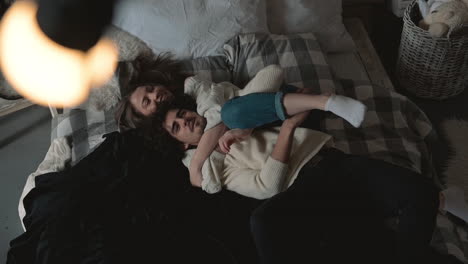 young romantic playful couple lying in bed hugging and wearing winter clothes