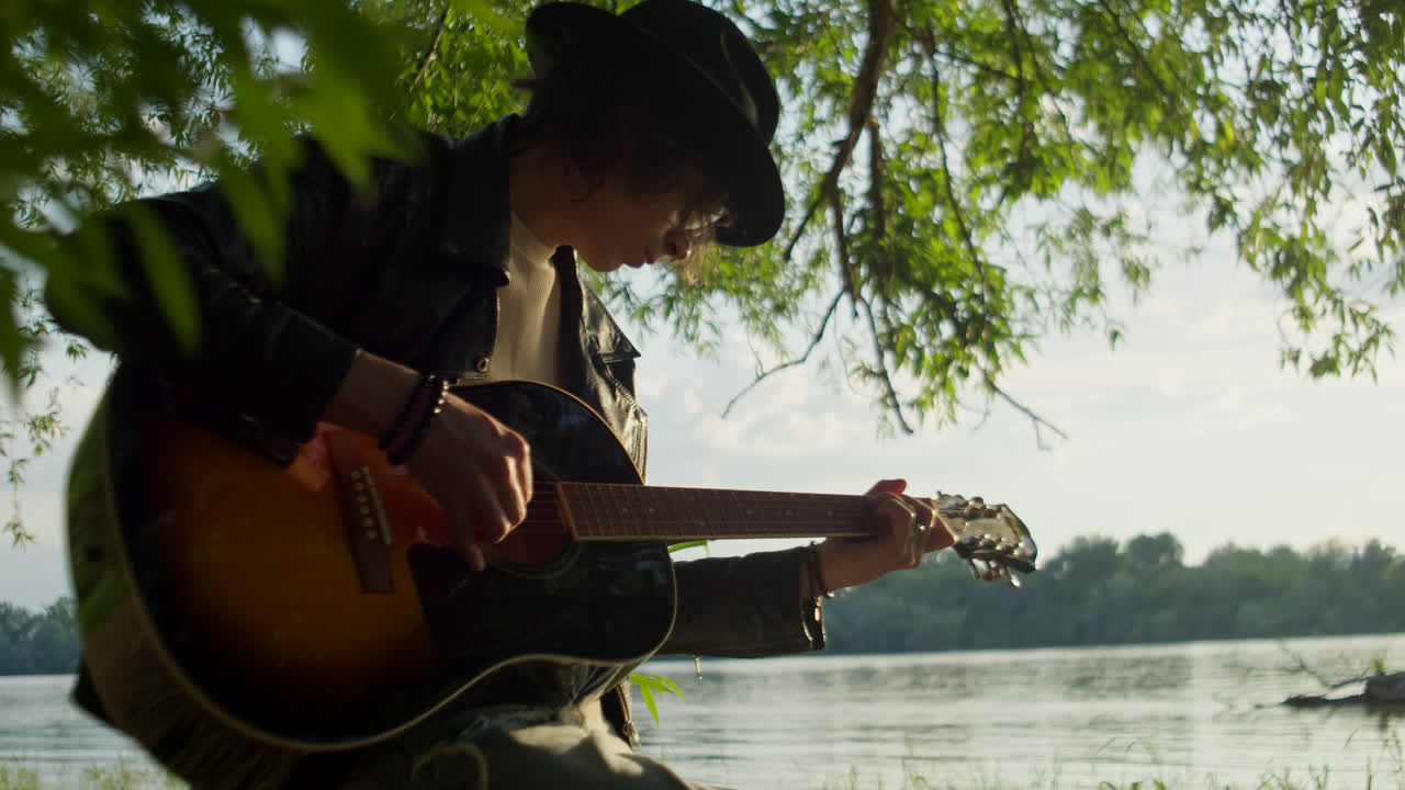 Young Musician Playing Acoustic Guitar by the River