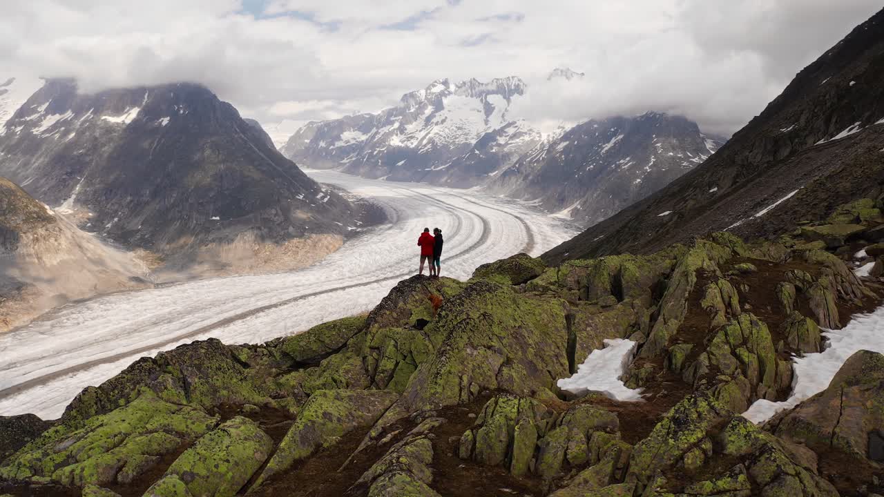 Stunning view of a couple standing on a rocky outcrop overlooking a glacier in Norway
