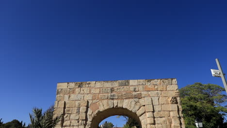 Día-Soleado-Que-Muestra-Las-Antiguas-Ruinas-Del-Arco-Romano-En-Dougga,-Fondo-De-Cielo-Azul-Claro,-Toma-Estática