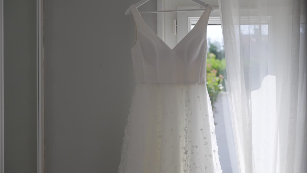 Stylish white wedding dress hanging in bride's room isolated
