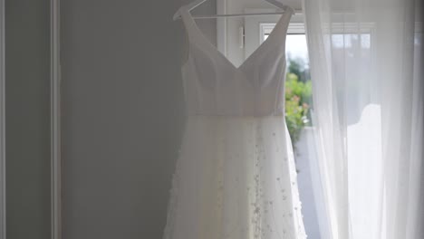 stylish white wedding dress hanging in bride's room isolated