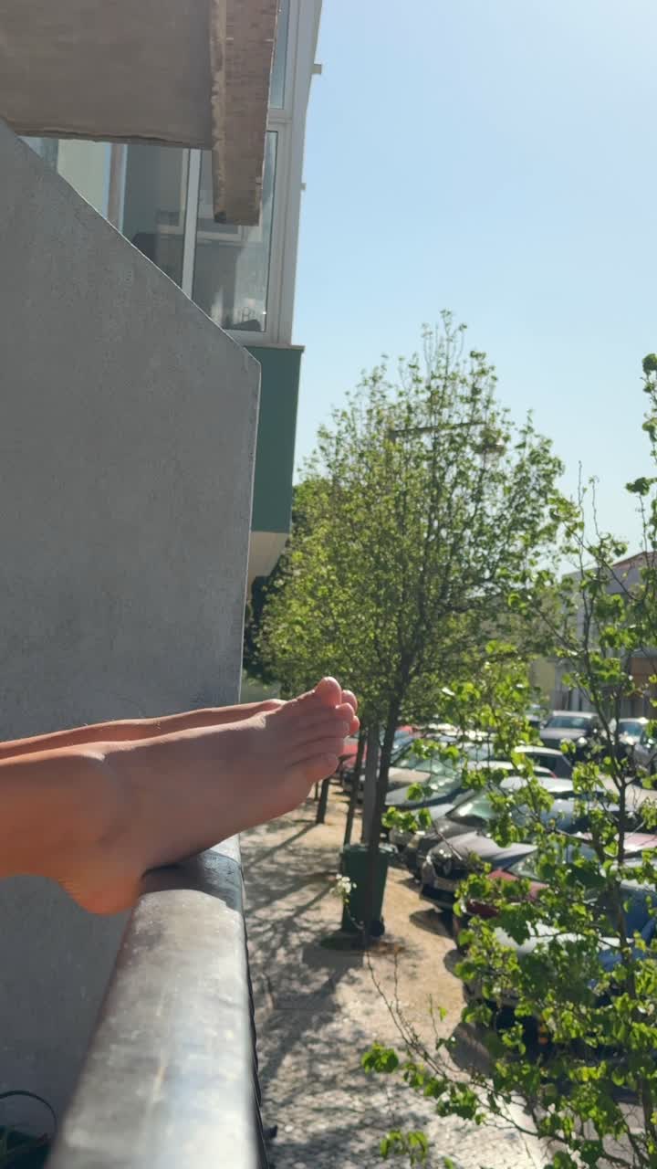 Feet resting on a balcony railing with a street view