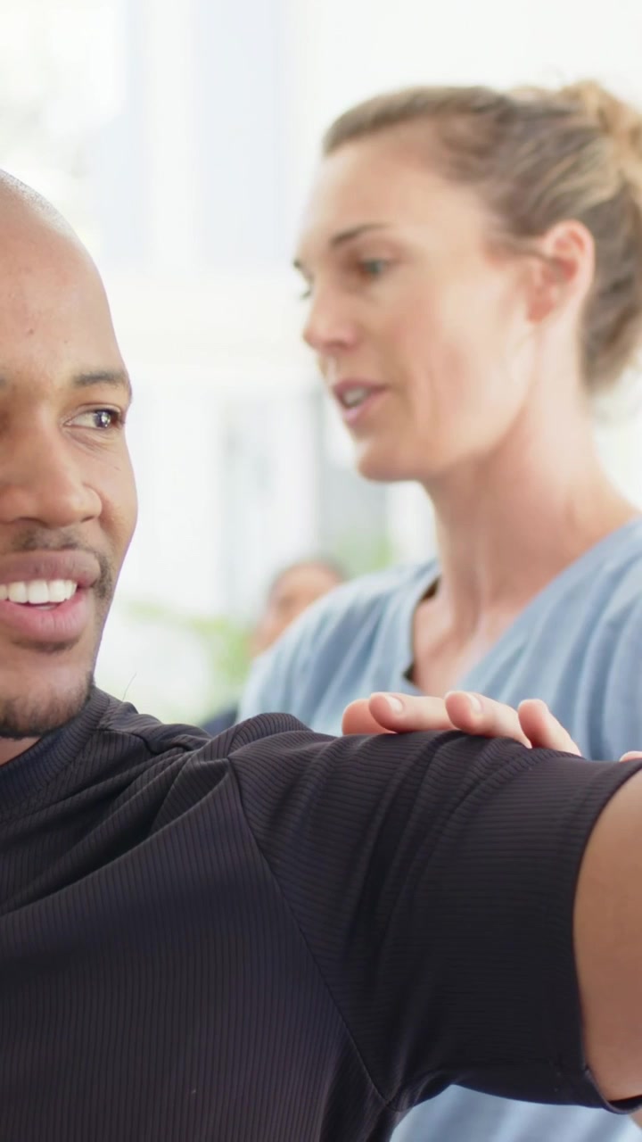 Vertical video: Coming woman blue tee urging man black tee holding arm by bright window, copy space