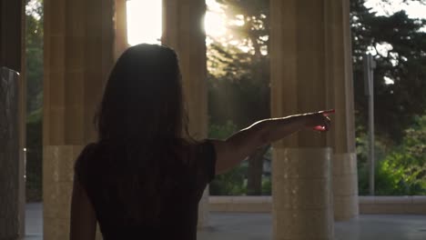 Young-woman-pointing-with-her-hand-away.-Girl-walking-outdoors-at-sunset