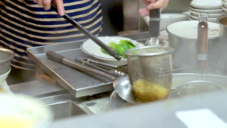 chef assembling noodle soup with vegetables