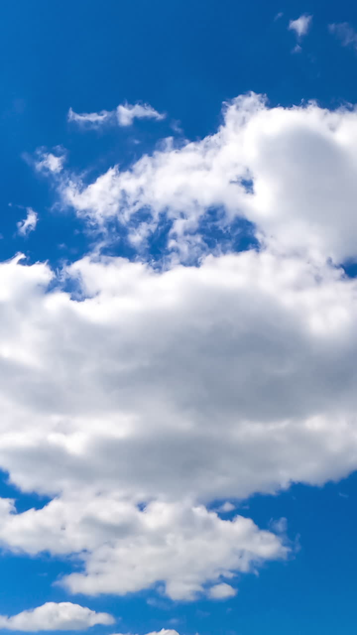 Wonderful blue sky with clouds quickly changing shapes. Beautiful cloudscape timelapse view from below. Vertical video