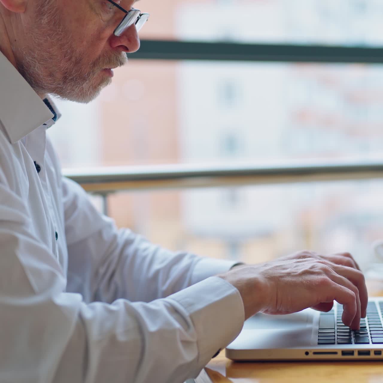 Senior businessman with laptop in office. Side view of a mature man finishing his work on a computer and taking a cup of coffee. Business concept. Close-up.