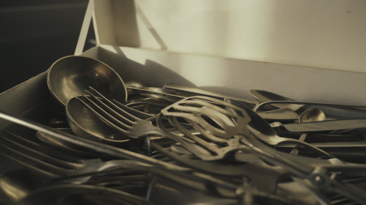 Detailed camera move over ornate silver cutlery arranged inside storage case. Ideal for heritage dining, antiques, and luxury lifestyle visuals