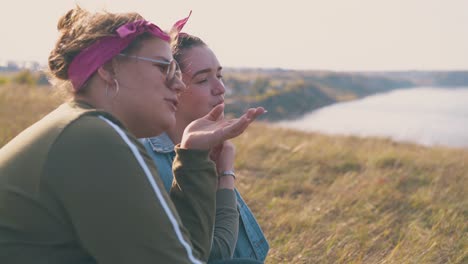 mujeres jóvenes felices hablan pasando el tiempo en la colina contra el río