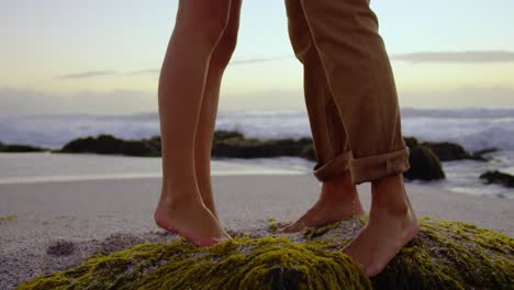 couple standing on rock at beach during sunset 4k