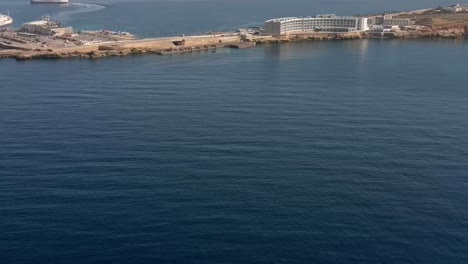 Toma-De-Drones-Con-Vistas-A-Cirkewwa-Malta-Con-Gozo-Ferry-Y-Hotel-En-Segundo-Plano