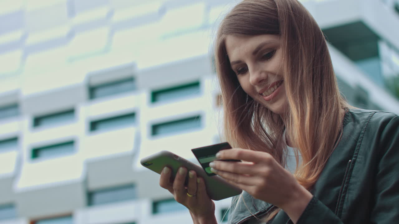Woman making mobile payment outside a modern building