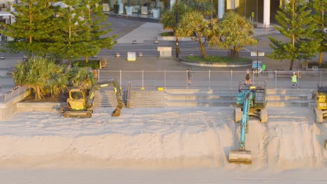 construction equipment and workers repair the beach at sunrise in gold coast, australia, with a calm and organized atmosphere