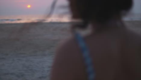 mujer viendo una hermosa puesta de sol en la playa