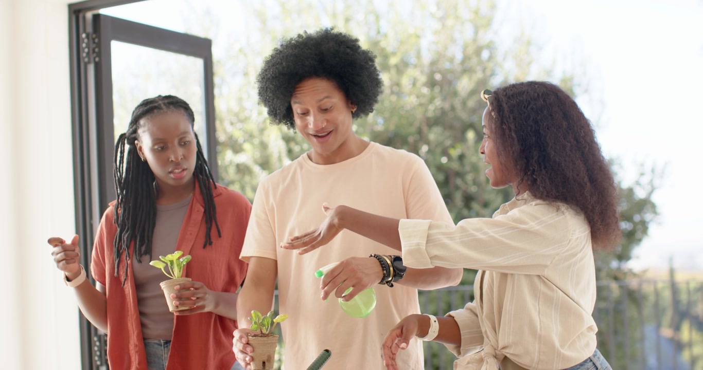 Amis afro-américains ramassant des semis, les plantant dans un pot en terre cuite à table avec une truelle