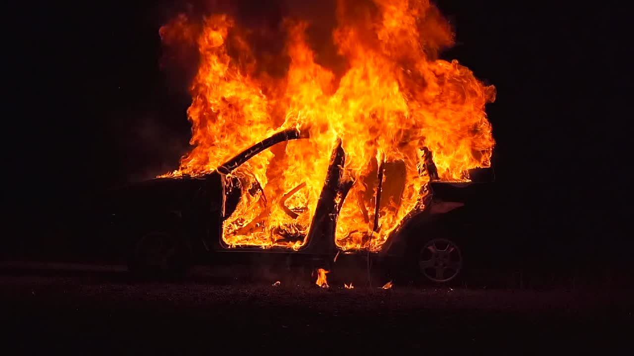burning car at night, left side, medium long shot, complete view