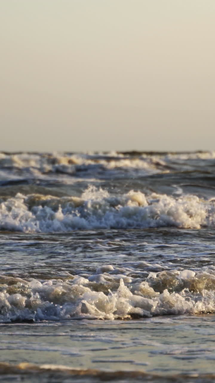 Storm in the sea. Big foamy waves crashing on the beach. Oceanic background at the edge of a coastline. Close-up. Vertical video