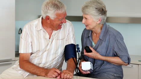 senior woman taking her husbands blood pressure