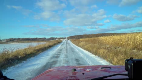 driver pov while driving a snowy rural road past corn fields on a sunny late autumn afternoon