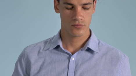 a handsome man demonstrating the proper wearing of surgical face mask standing against light blue background - coronavirus pandemic - closeup shot