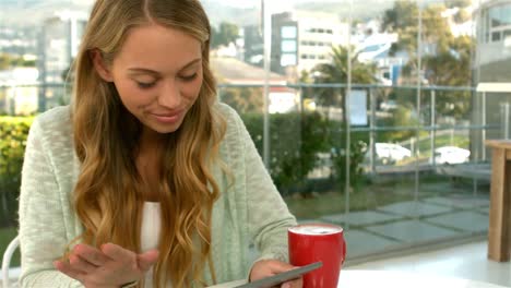 Pretty-girl-using-tablet-and-smiling-at-the-camera