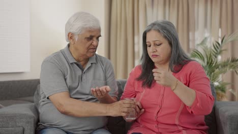 um velho marido indiano cuidadoso a dar remédio à sua mulher doente.