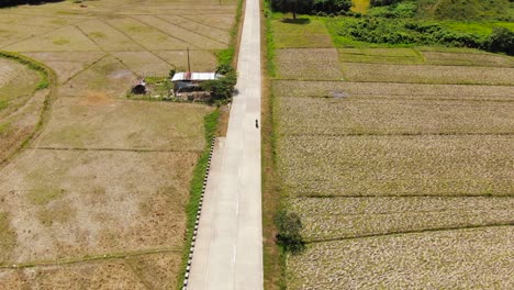 Motorbike-driving-at-an-empty-street-with-farmland-around