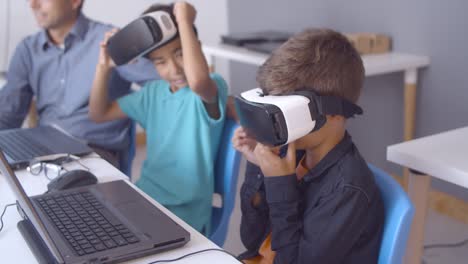 schoolboys putting on vr glasses at desk