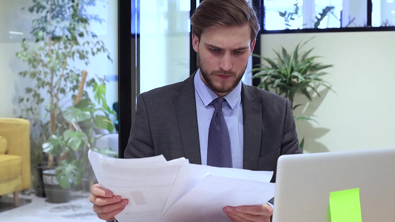 Young Businessman Reading Documents in Modern Office