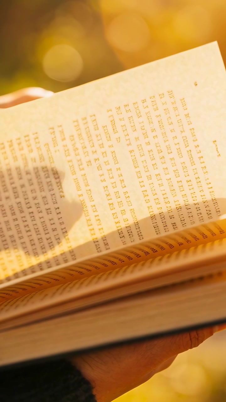 Vertical video: Adjusting grip, reader turning page to read on in garden sun, pages and knit sleeve