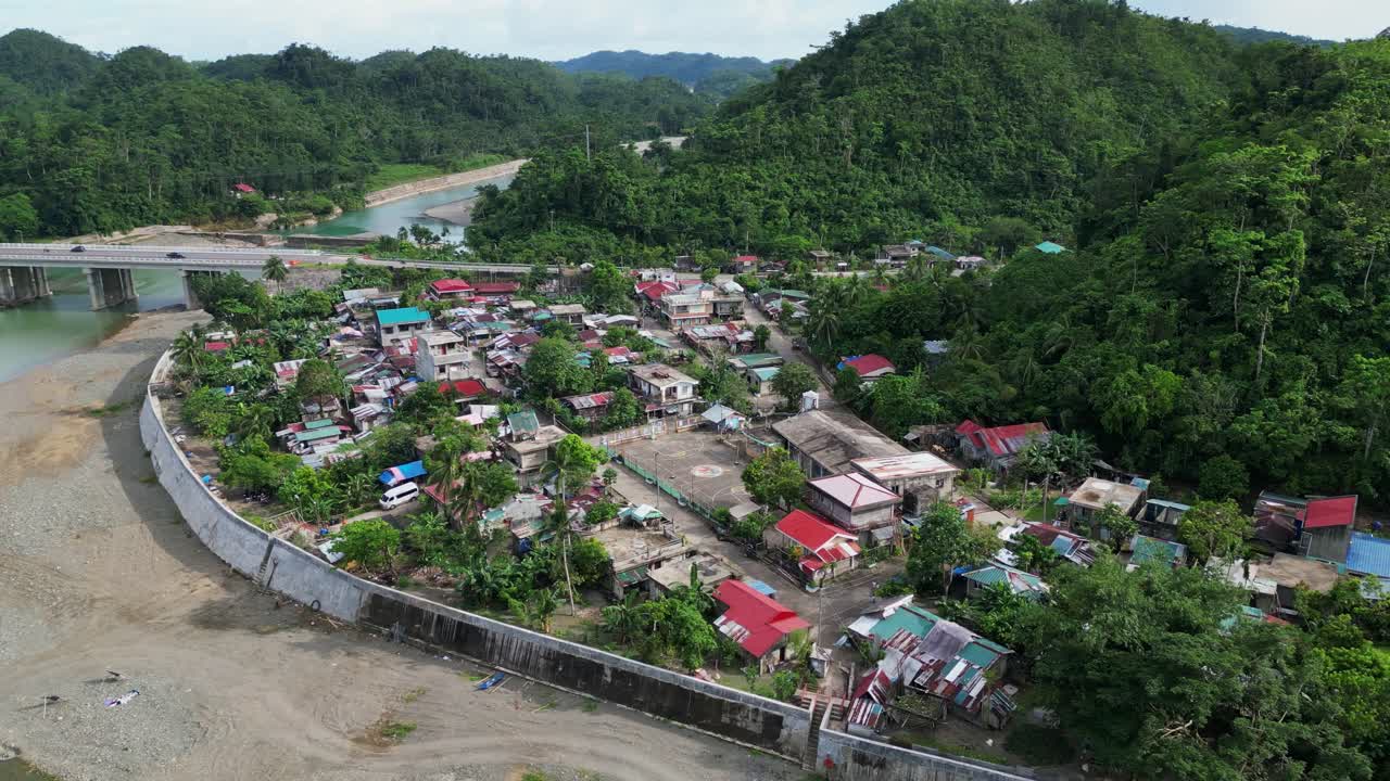 Idyllic aerial orbit of Santo Domingo village alongside lush hills and Pajo River in Virac, Catanduanes