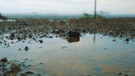 A-puddle-of-water-on-the-dirt-road-of-Curacao-with-the-beautiful-landscape-in-the-background---Close-up