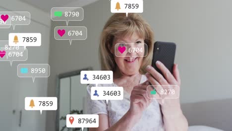 Animation-Von-Social-Media-Symbolen-Gegen-Eine-Kaukasische-Seniorin,-Die-Zu-Hause-Ihr-Smartphone-Nutzt