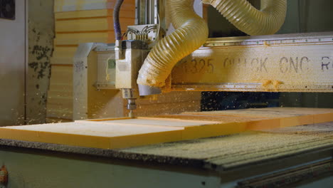 active cnc machine shaping foam with dust extractor in a woodworking shop